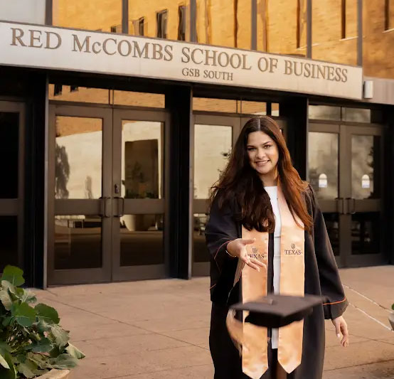 Valles in graduation gown in front of McCombs School