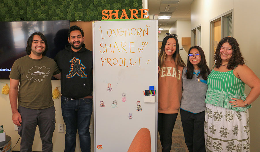 share students in fromt of sign smiling
